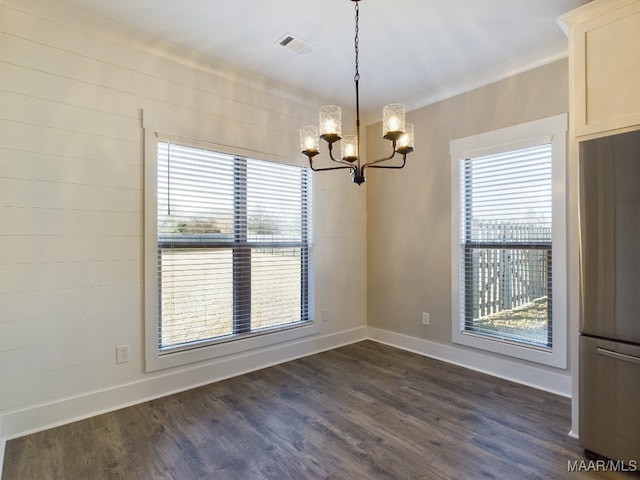 unfurnished dining area with plenty of natural light, dark hardwood / wood-style flooring, ornamental molding, and an inviting chandelier