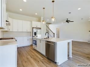 kitchen with stainless steel appliances, light countertops, light wood-style floors, and white cabinetry