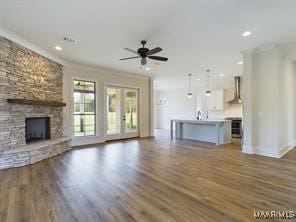 unfurnished living room featuring baseboards, a ceiling fan, wood finished floors, a stone fireplace, and recessed lighting