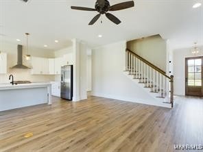 unfurnished living room with stairs, wood finished floors, a ceiling fan, and recessed lighting