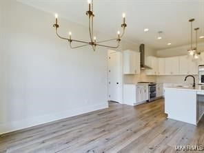 kitchen with white cabinetry, wall chimney exhaust hood, stove, and light countertops