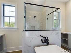 full bath with a marble finish shower, a freestanding bath, and vanity