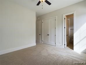 unfurnished bedroom with a closet, carpet, a ceiling fan, and baseboards