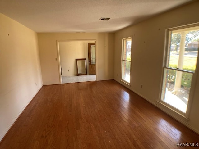 spare room with a wealth of natural light and hardwood / wood-style flooring