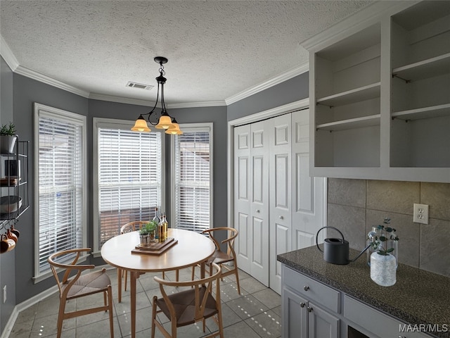 tiled dining room featuring a textured ceiling and ornamental molding