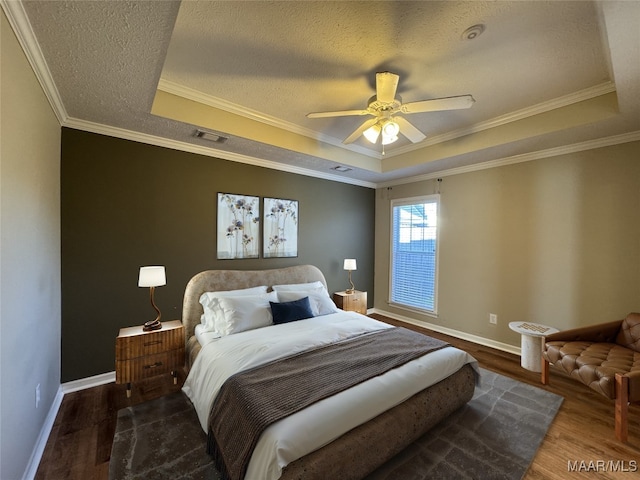 bedroom with ceiling fan, dark wood-type flooring, crown molding, and a tray ceiling