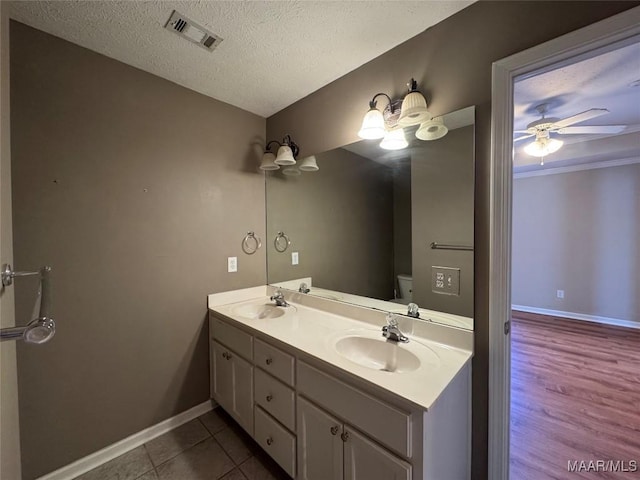 bathroom with a textured ceiling, tile patterned flooring, vanity, toilet, and ceiling fan