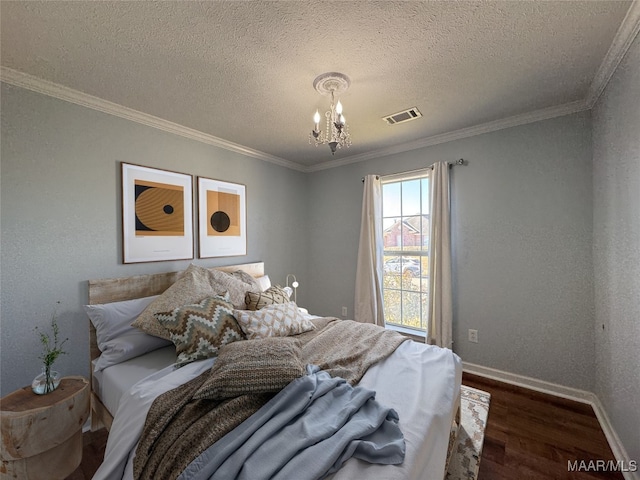 bedroom with dark wood-type flooring, a textured ceiling, ornamental molding, and a chandelier