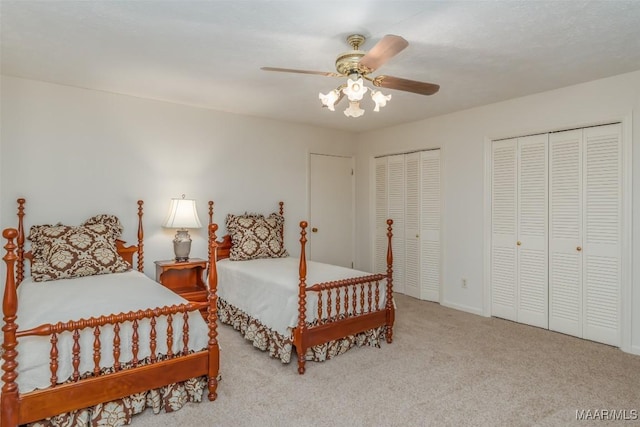 carpeted bedroom with ceiling fan and multiple closets