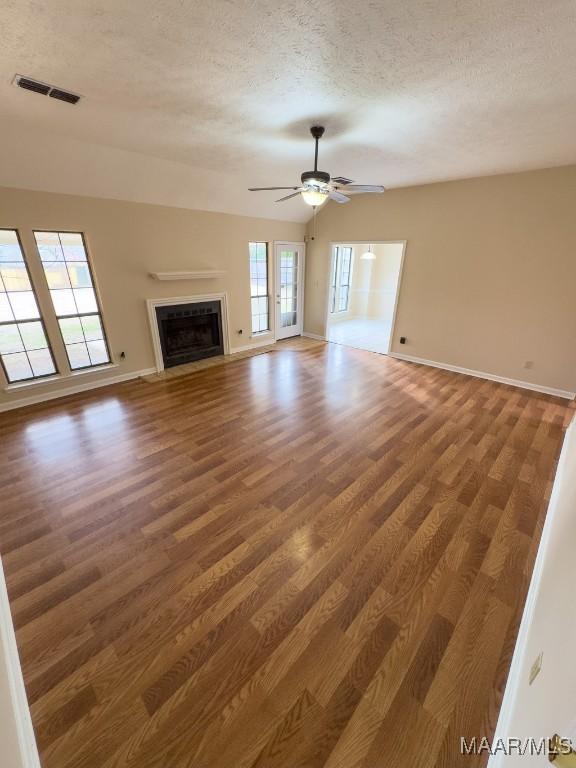 unfurnished living room with ceiling fan, dark wood-type flooring, and a textured ceiling