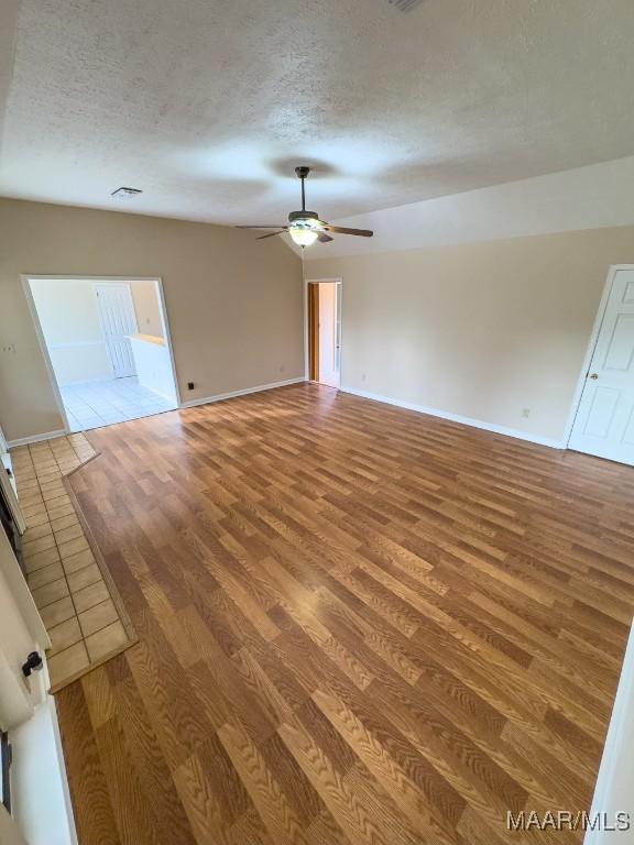 unfurnished living room featuring ceiling fan, a textured ceiling, and hardwood / wood-style floors