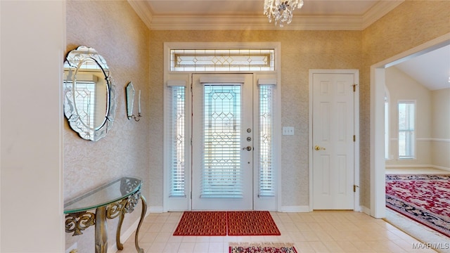 tiled foyer entrance featuring plenty of natural light, ornamental molding, and a chandelier