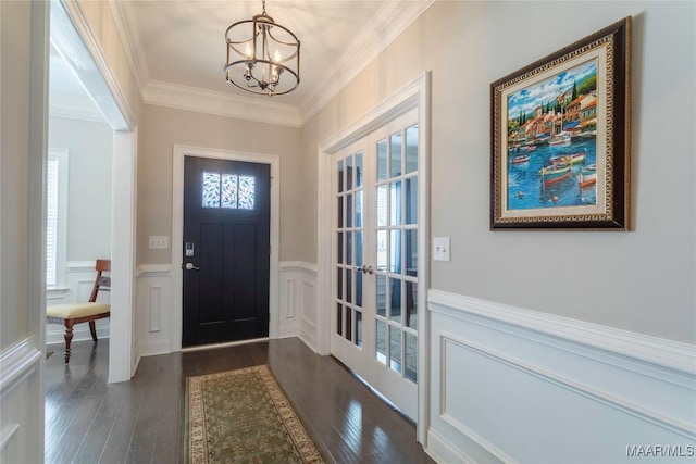 entryway with dark wood-type flooring, ornamental molding, french doors, and a notable chandelier