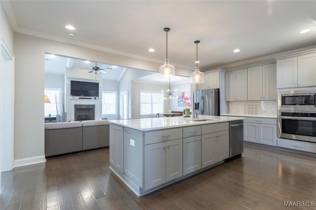 kitchen featuring tasteful backsplash, hanging light fixtures, an island with sink, gray cabinetry, and stainless steel appliances