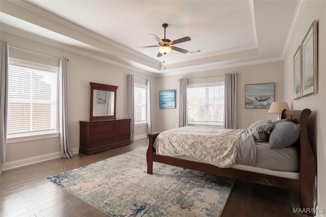 bedroom with ceiling fan, a raised ceiling, and multiple windows