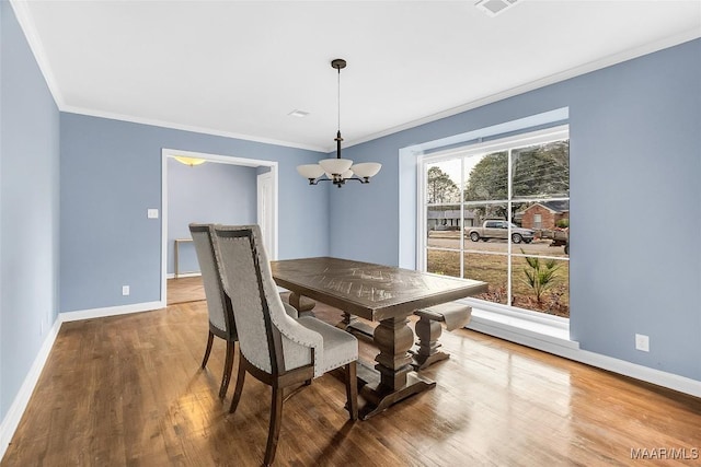 dining area with crown molding, wood-type flooring, and a notable chandelier