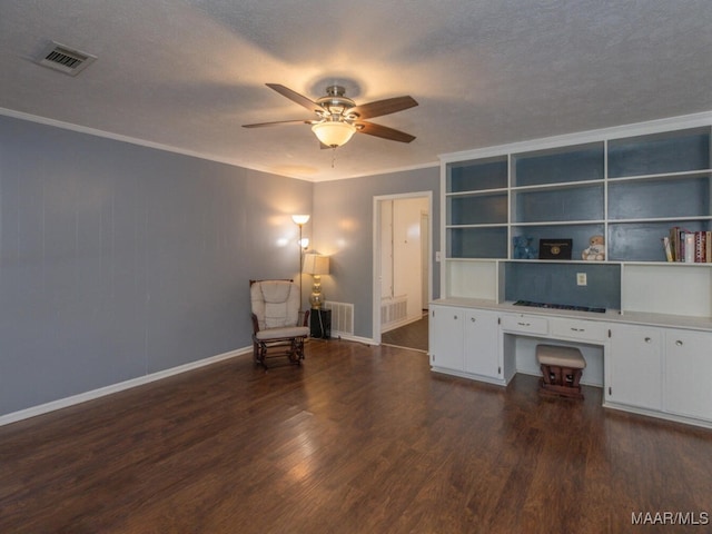 unfurnished office with ceiling fan, dark hardwood / wood-style floors, crown molding, and built in desk