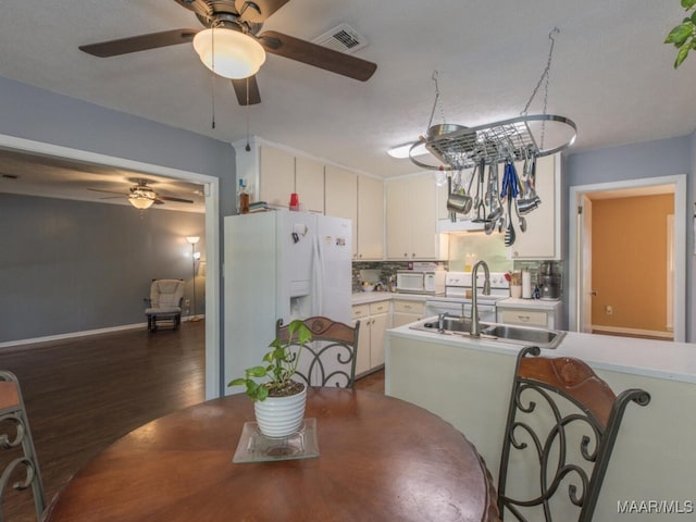 kitchen with an inviting chandelier, white cabinetry, tasteful backsplash, white appliances, and sink