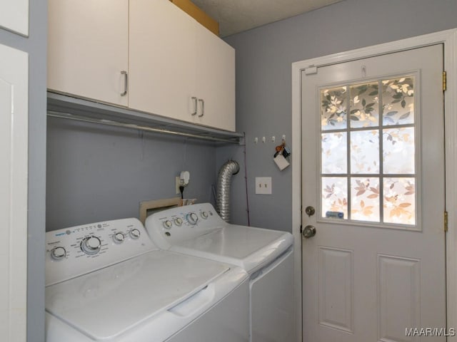 washroom featuring cabinets and washer and clothes dryer