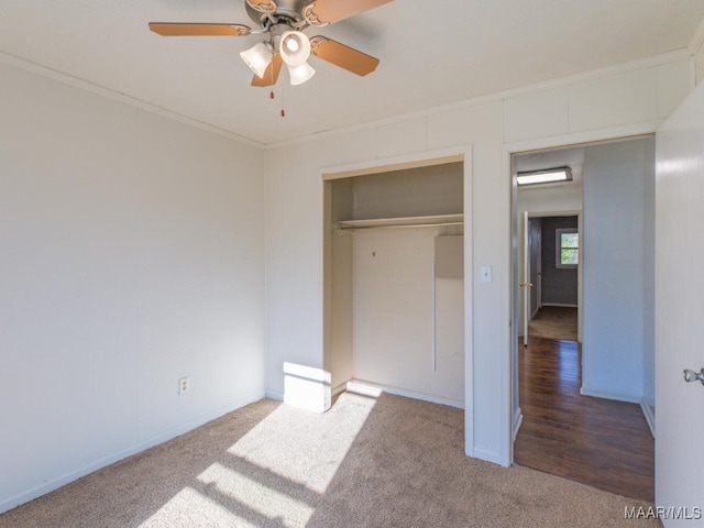 unfurnished bedroom with ceiling fan, a closet, carpet floors, and crown molding