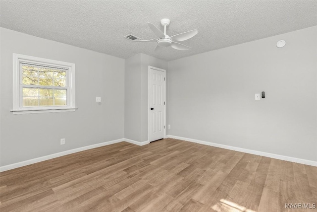 empty room with ceiling fan, light wood-type flooring, and a textured ceiling