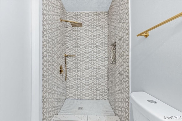 bathroom featuring toilet, a textured ceiling, and a tile shower