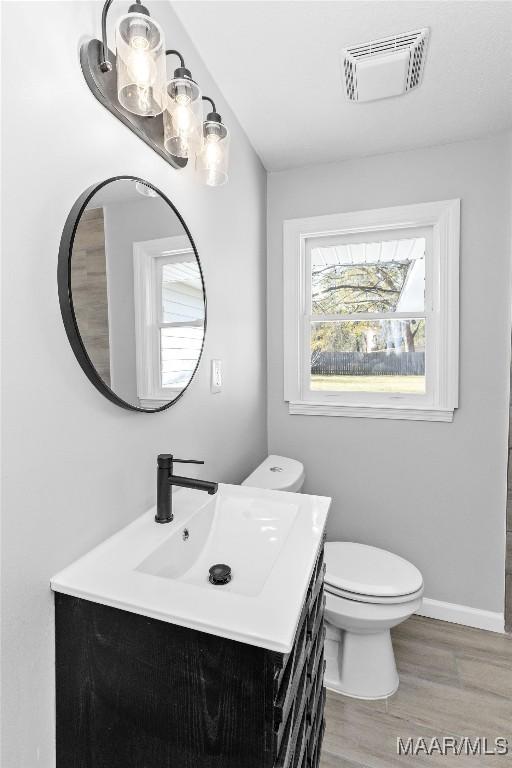 bathroom featuring toilet, hardwood / wood-style flooring, and vanity