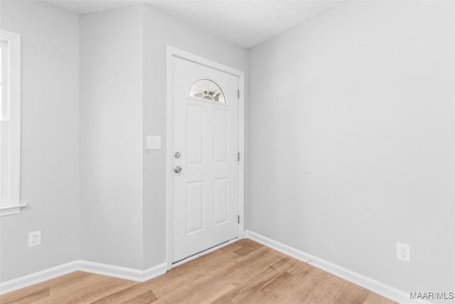 foyer with a textured ceiling, a wealth of natural light, and light hardwood / wood-style floors