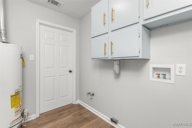 laundry room featuring hookup for a washing machine, gas water heater, a textured ceiling, hookup for an electric dryer, and cabinets