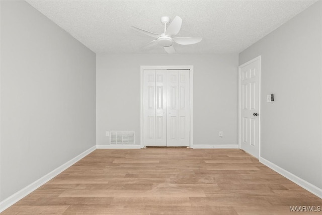 unfurnished bedroom featuring a textured ceiling, ceiling fan, a closet, and light hardwood / wood-style floors