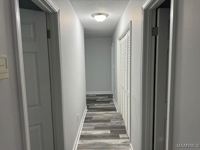 hall featuring a textured ceiling and dark hardwood / wood-style flooring