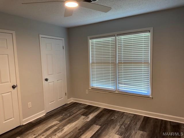 unfurnished bedroom with a textured ceiling, ceiling fan, and dark hardwood / wood-style flooring