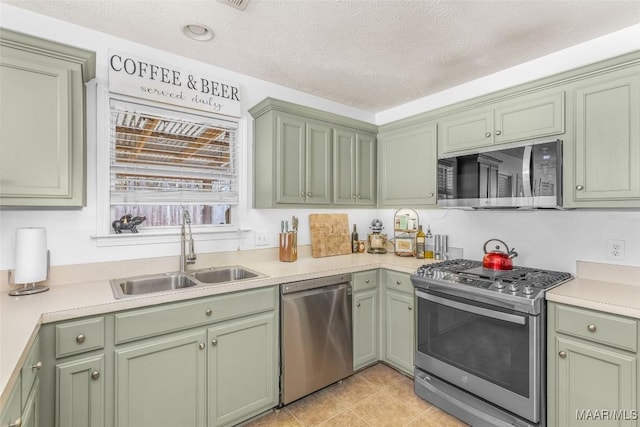 kitchen with sink, stainless steel appliances, green cabinetry, and a textured ceiling