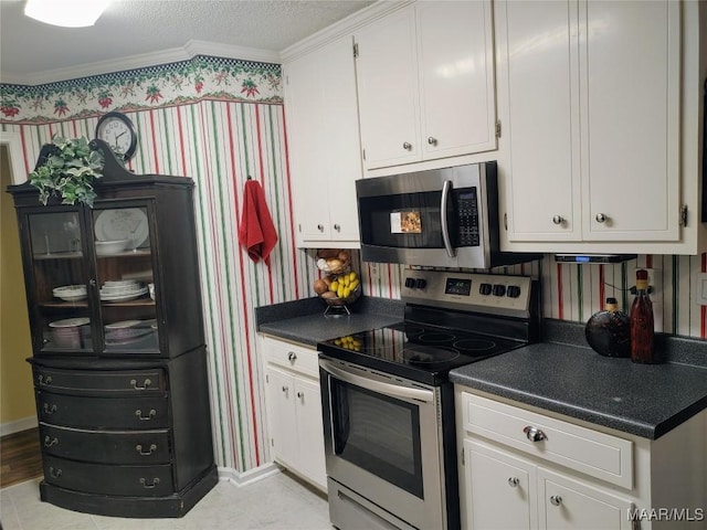 kitchen featuring a textured ceiling, crown molding, stainless steel appliances, and white cabinetry