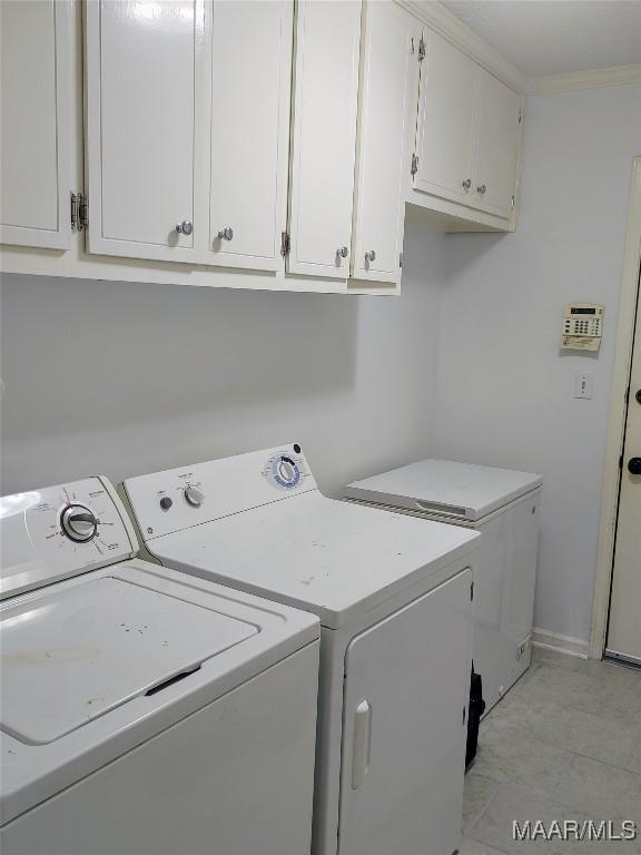 laundry area featuring washer and dryer, cabinets, and crown molding