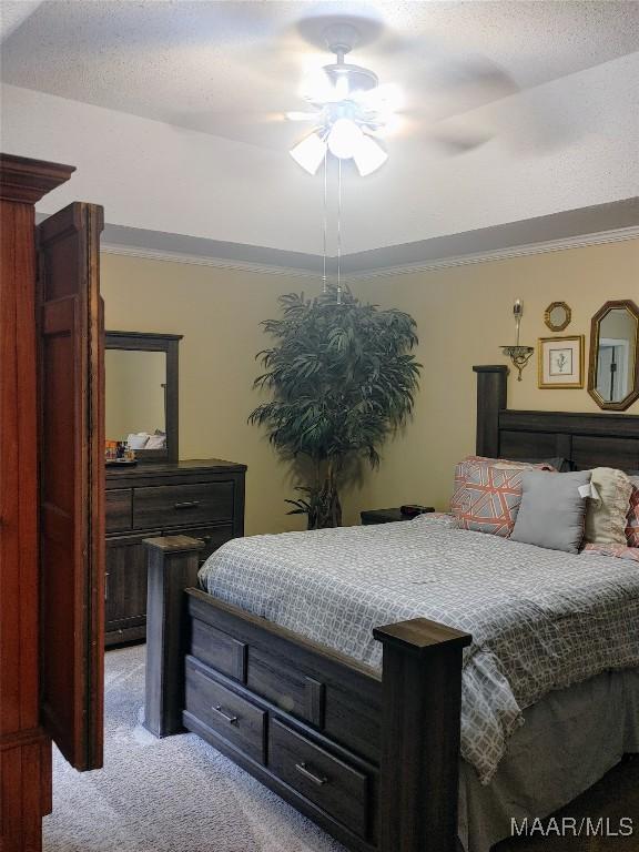 bedroom with ceiling fan, light colored carpet, and a textured ceiling