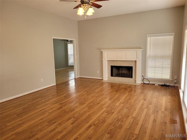 unfurnished living room with ceiling fan, light wood-type flooring, and a tile fireplace