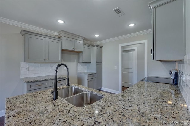 kitchen with gray cabinets, sink, decorative backsplash, light stone counters, and crown molding