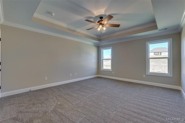 empty room with a raised ceiling, crown molding, carpet floors, and ceiling fan