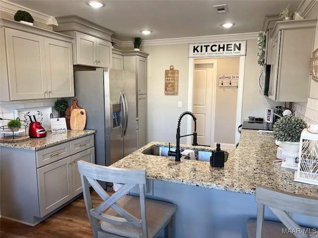 kitchen featuring ornamental molding, gray cabinetry, light stone counters, and a kitchen bar