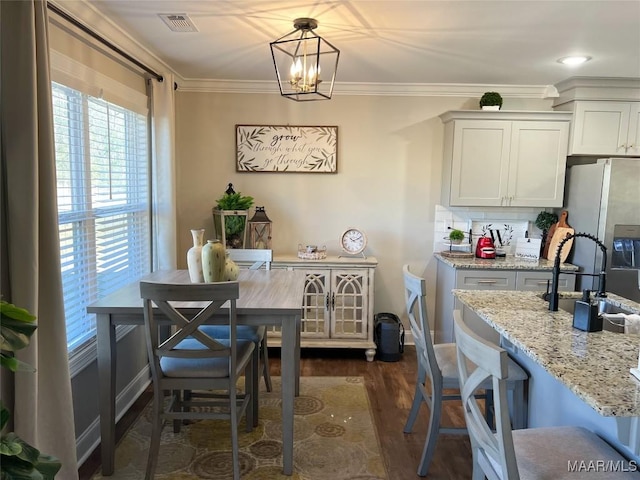 dining room with dark hardwood / wood-style flooring, ornamental molding, and an inviting chandelier