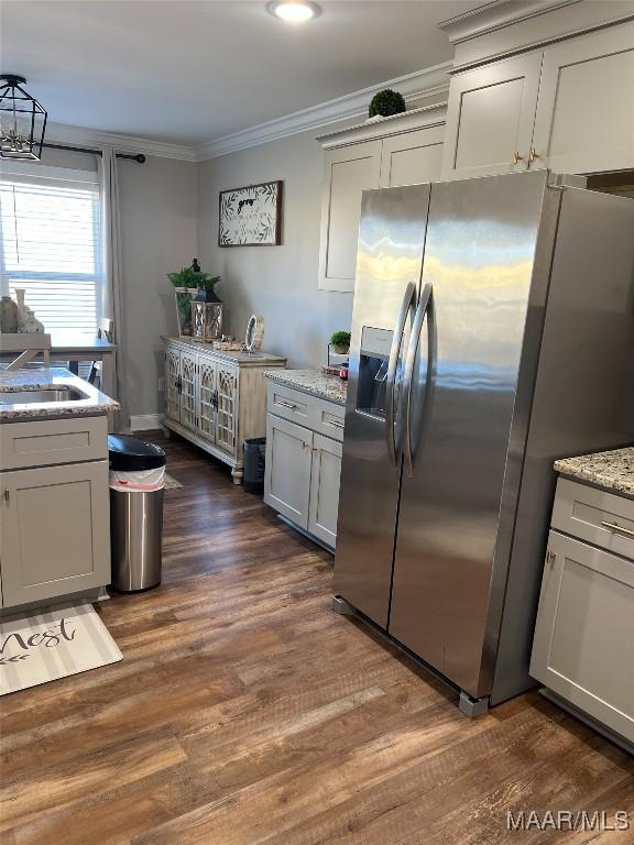 kitchen with light stone countertops, sink, stainless steel fridge, and dark hardwood / wood-style flooring