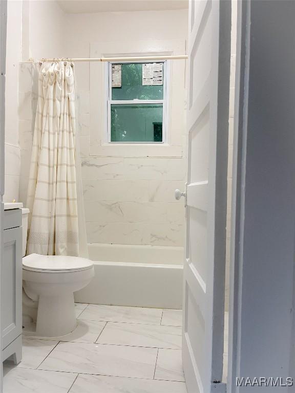 bathroom featuring marble finish floor, vanity, toilet, and shower / bathtub combination with curtain