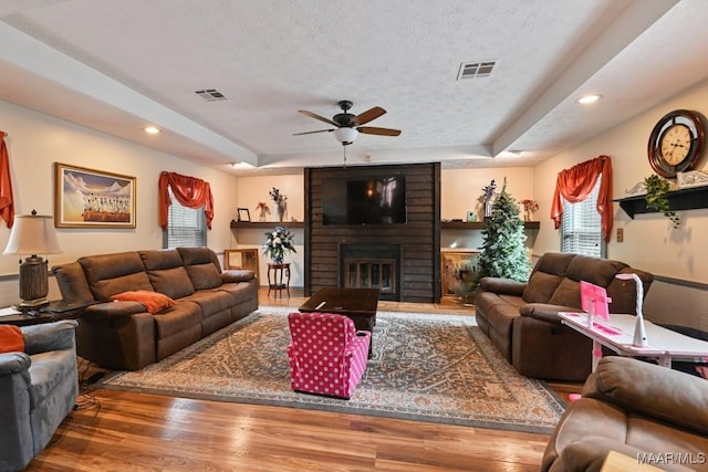 living room featuring a textured ceiling, a fireplace, hardwood / wood-style floors, and a tray ceiling