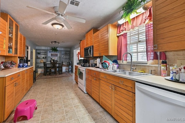 kitchen with ceiling fan, decorative backsplash, sink, white appliances, and a textured ceiling