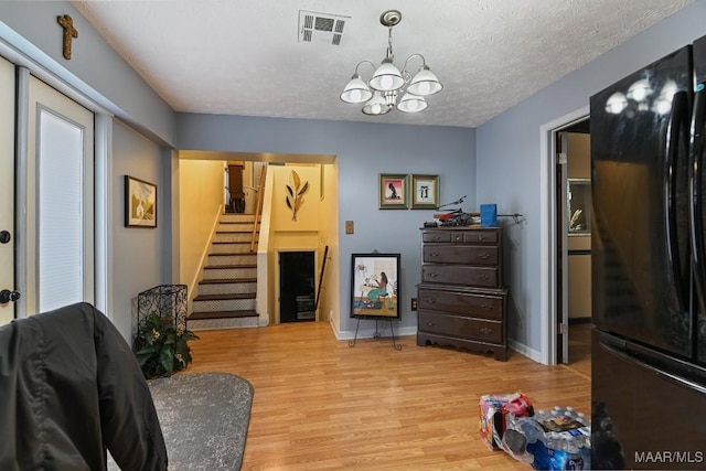 sitting room featuring light hardwood / wood-style floors, a textured ceiling, and a chandelier