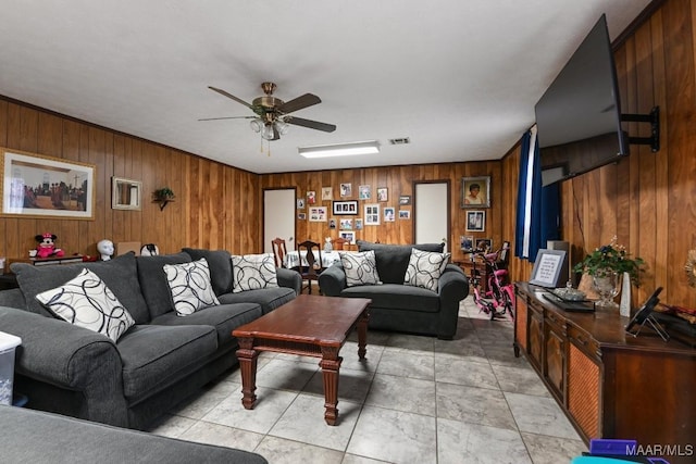 tiled living room with ceiling fan and wood walls