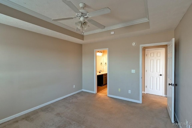 unfurnished bedroom featuring light carpet, a raised ceiling, ceiling fan, ensuite bathroom, and crown molding