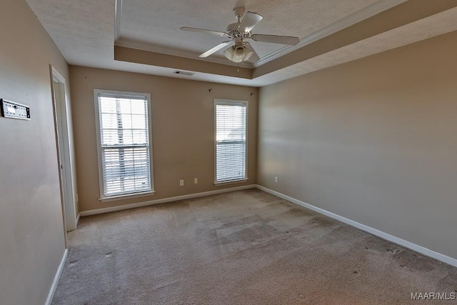 carpeted spare room with ceiling fan, a textured ceiling, ornamental molding, and a raised ceiling