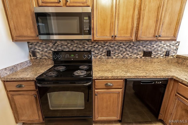 kitchen featuring tasteful backsplash, light stone counters, and black appliances